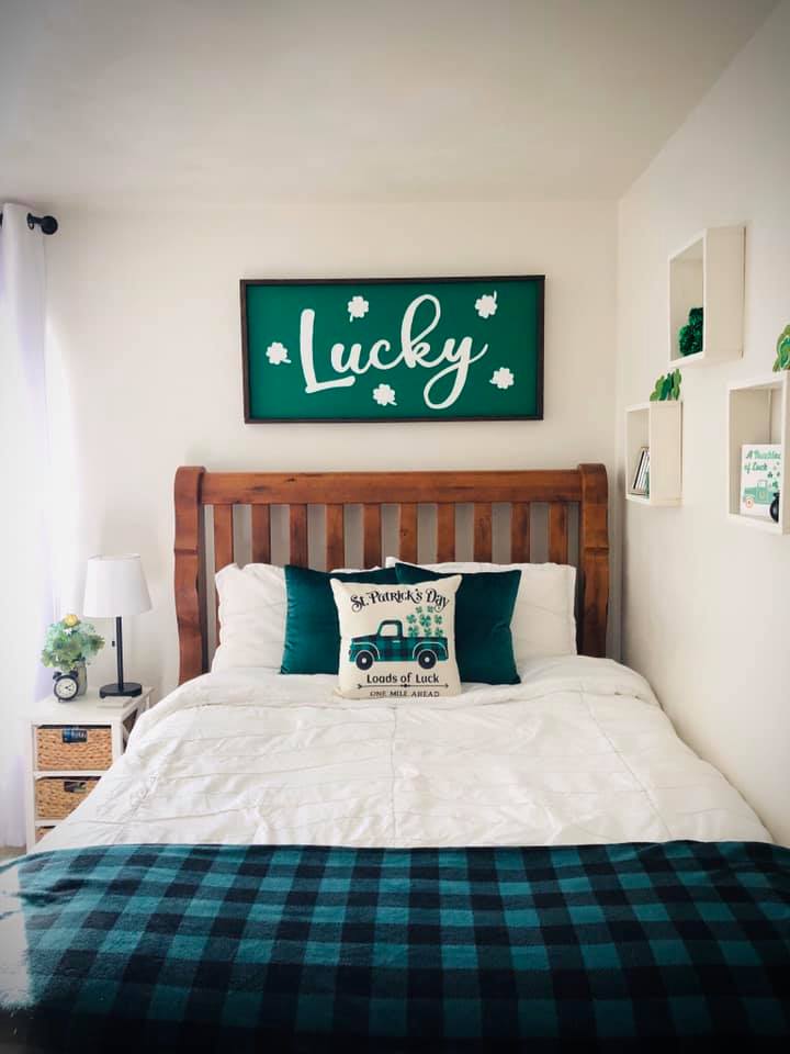 St. Patrick's themed bedroom design featuring white bedding topped with green accent pillows and throw blanket along with a lucky green headboard sign