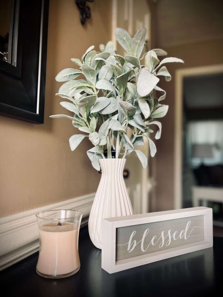 Beautifully staged main entrance table featuring greenery, a candle, and sign depicting the work "blessed" - occupied staging