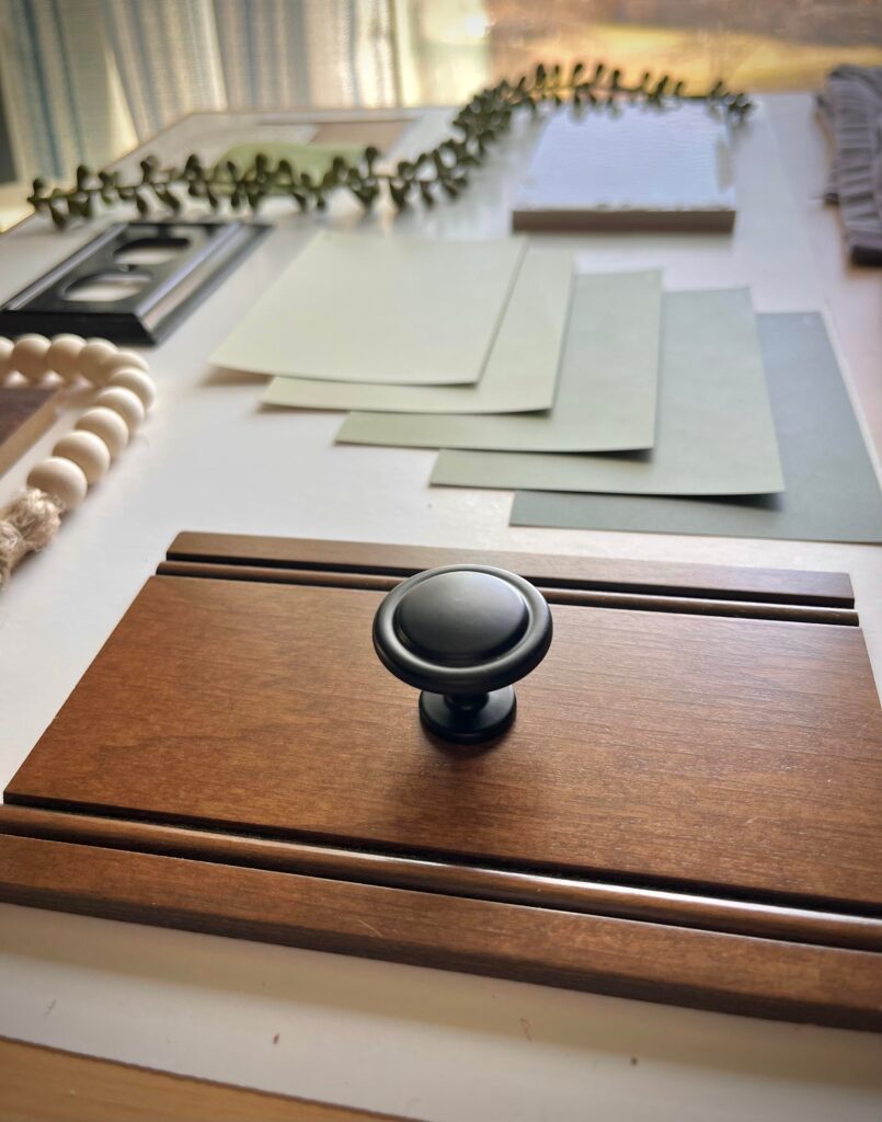 Interior Design Material Board featuring a green, cream, and nautual color scheme with black hardware and dark oak cabinetry